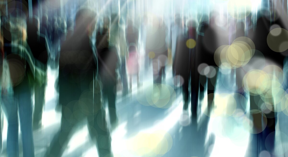 Menschenmenge in Bewegung auf einer Straße oder einem Gehweg. Die Personen sind unscharf dargestellt. Durch die Bewegungsunschärfe wirken die Menschen als Silhouetten, die sich in verschiedene Richtungen bewegen.