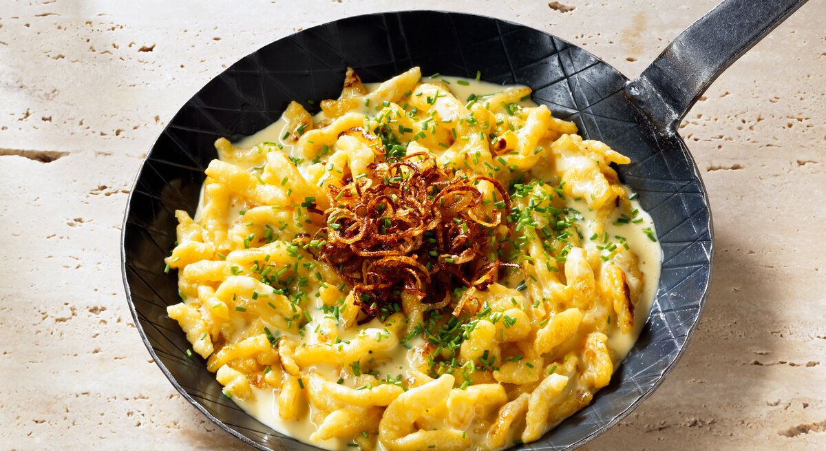 Blick auf eine gusseiserne Pfanne mit Käsespätzle.