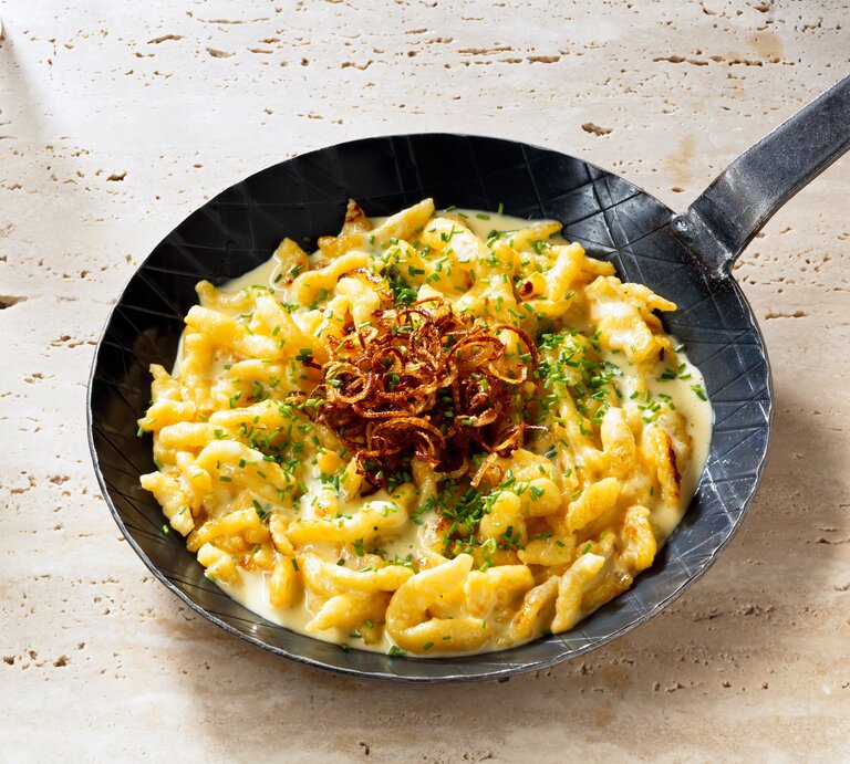 Blick auf eine gusseiserne Pfanne mit Käsespätzle. | © iStock/ JackJelly
