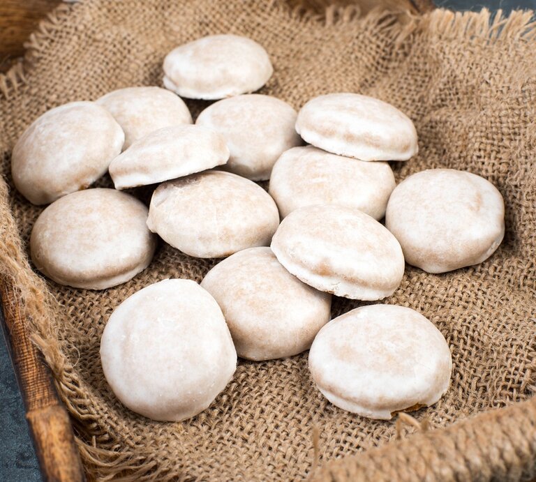 Vierzehn Pfeffernüsse / Untergrund grobes Sackleinen in einer Kiste aus Holz / Draufsicht, schräg | © Shutterstock / Berit Kessler