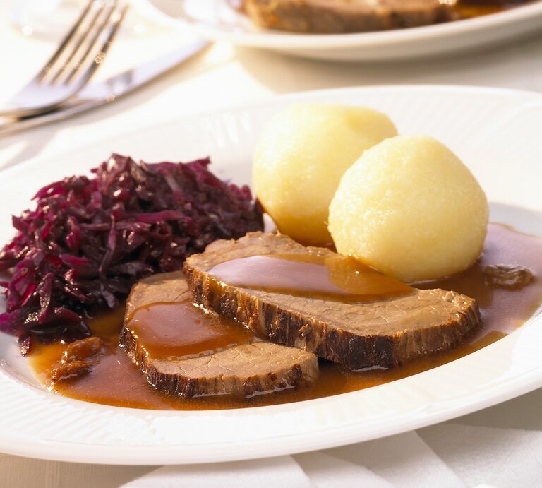 Rheinischer Sauerbraten mit Rotkohl und Kartoffelklößen auf weißem Teller.  | © StockFood / Rees, Peter