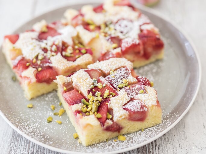 Drei quadratische Stücke Rhabarberkuchen vom Blech auf einem runden Teller. | © StockFood / Wischnewski, Jan