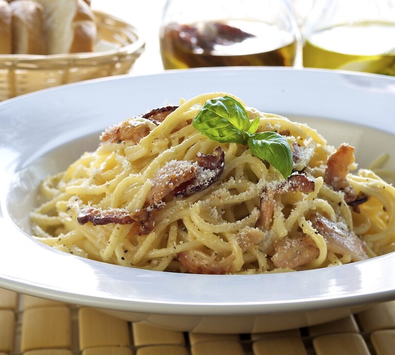 Weißer Pasta-Teller befüllt mit original Spaghetti Carbonara mit italienischem Speck und geriebenem Hartkäse. | © iStock/ ShyMan