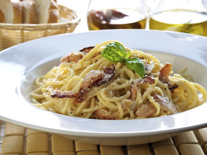 Weißer Pasta-Teller befüllt mit original Spaghetti Carbonara mit italienischem Speck und geriebenem Hartkäse. | © iStock/ ShyMan