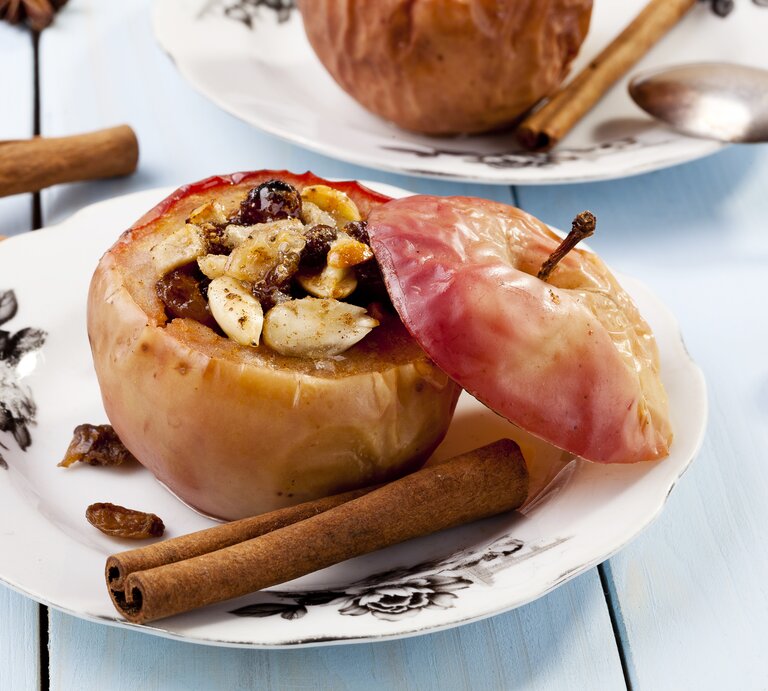 Ein gefüllter Bratapfel mit Knusperhaube auf weißem Teller.  | © iStock/gkrphoto