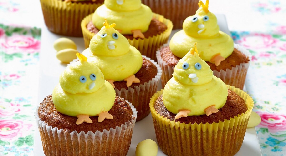 Gelbe Küken-Cupcakes mit blauen Augen und orangen Füßen auf einer Etagere.