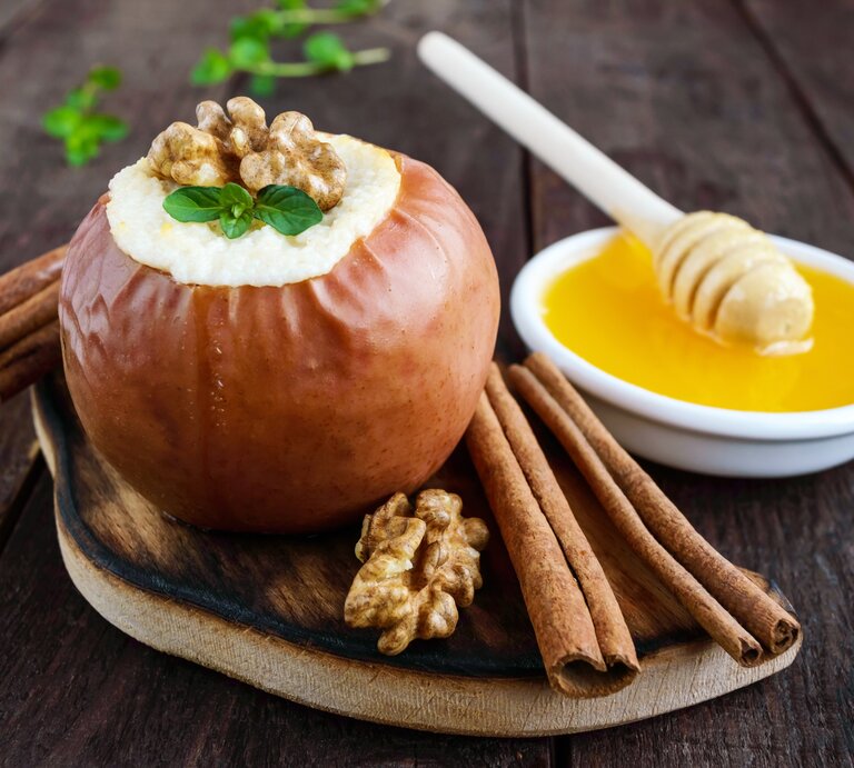 Bratapfel-Mousse mit Vanillesoße in einem Bratapfel / Zimstangen / Walnusskerne | © iStock/Maryna Iaroshenko