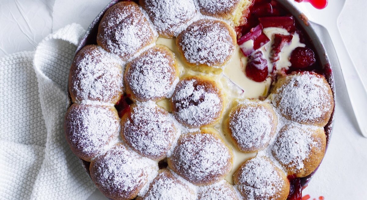 Draufsicht: Ein Rhabarber-Erdbeer-Dessert mit Milchbrötchen und Vanillesoße in einer runden Form aus Metall.