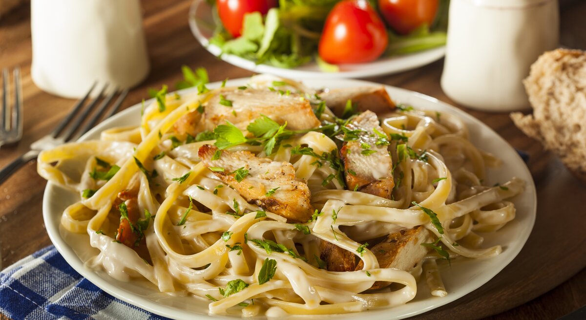 Ein Teller mit Pasta in Hähnchen-Sahnesoße, bestreut mit Kräutern. 
