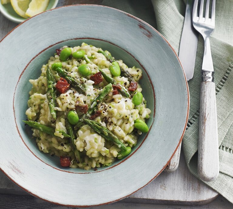 Ein hellblauer Teller mit dem grünen Risotto auf einem grauen Holztisch mit hellen Tischdecken. Alles direkt von oben fotografiert. | © StockFood / Luck, Alex