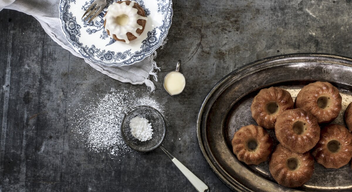 Die kleinen Kuchen auf einem dunklen Tisch mit blauweißem Teller. Alles direkt von oben fotografiert.