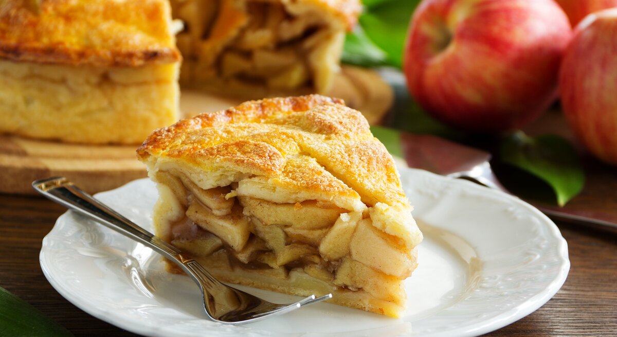 Ein Stück gedeckter Apfelkuchen mit Füllung auf Teller.
