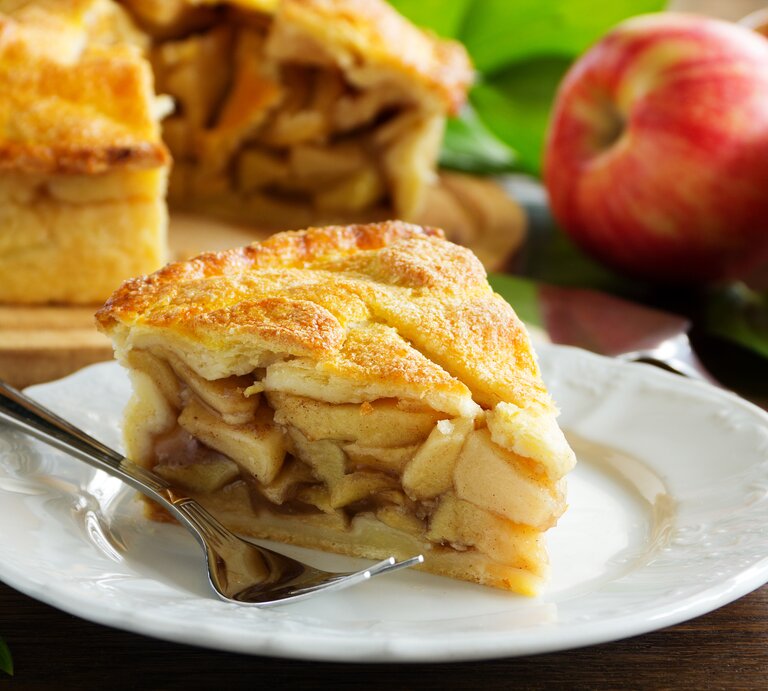 Ein Stück gedeckter Apfelkuchen mit Füllung auf Teller. | © iStock/ Lesyy