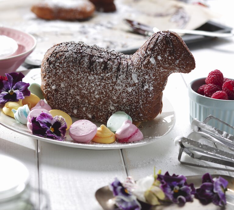 Auf einem hellen Holztisch liegt ein gebackenes Osterlamm mit Baisertupfen. | © StockFood / Weymann, Frank