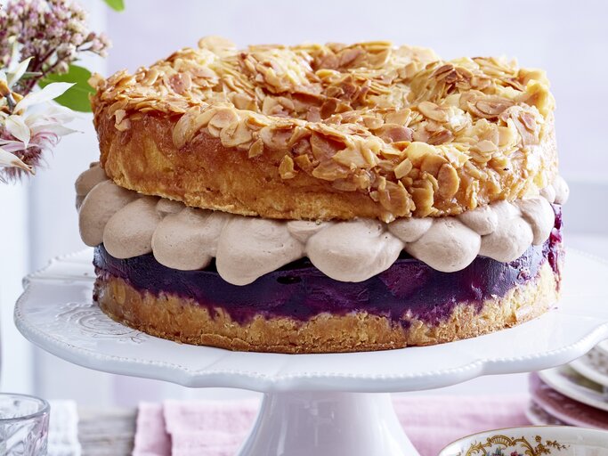 Frontal fotografierter Bienenstich mit Nougatsahne und Rotwein-Birnenkompott auf einer Etagere. | © EAT CLUB/Isabell Triemer
