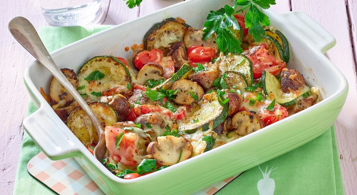 Pilzgratin in einer Auflaufform auf weißem Hintergrund. 