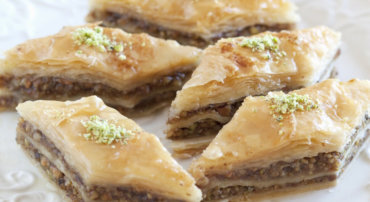 Rautenförmiges Baklava auf einem weißen Pozellanteller nah und von vorne fotografiert