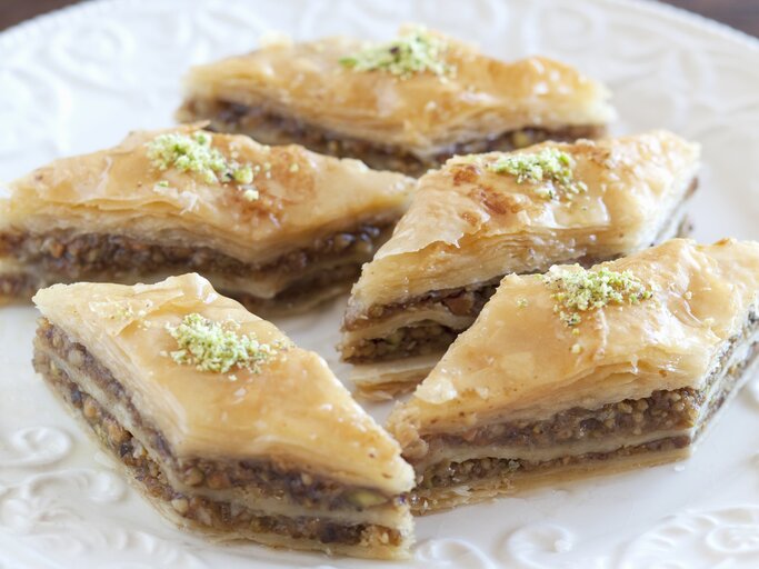 Rautenförmiges Baklava auf einem weißen Pozellanteller nah und von vorne fotografiert | © StockFood / Hammond, Louise