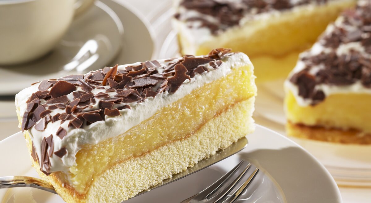 Ein Stück der schwedische Apfeltorte mit Sahne und Schokoraspeln auf einem Kuchenteller von schräg oben fotografiert. 