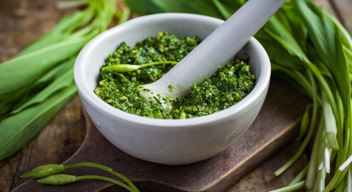 Weißer Mörser gefüllt mit hausgemachtem Bärlauchpesto. 