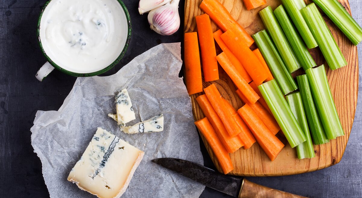 Gorgonzola-Dip und Rohkost-Sortiment auf Untergrund. 
