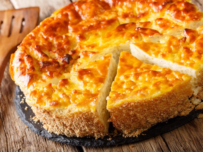 Ein angeschnittener Milchreiskuchen auf Holztisch.  | © iStock.com/ALLEKO
