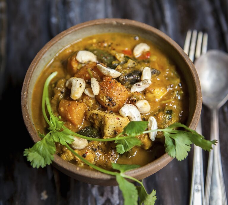 Cremiges Süßkartoffel-Curry mit Hähnchen und Cashews, garniert mit frischem Koriander in einer Schale auf dunklem Holztisch. | © StockFood/Thorpe, Lara Jane