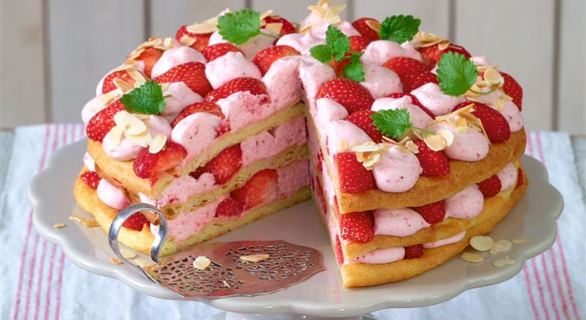 Windbeutel-Torte mit Erdbeer-Sahne auf einem weißen Tortenteller.