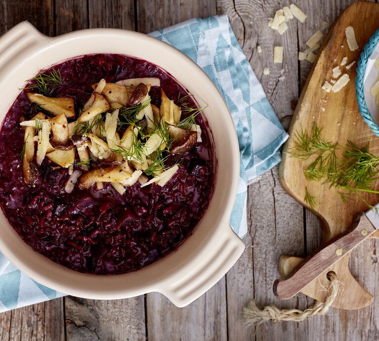 Rote Bete Risotto auf hölzernem Hintergrund. Rechts davon Parmesan. | © StockFood/Eat Club; Isabell Triemer