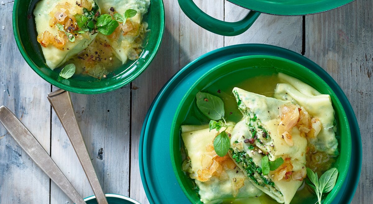 Grünkohl Maultaschen in grünen Schüsselchen auf grauem Hintergrund. 