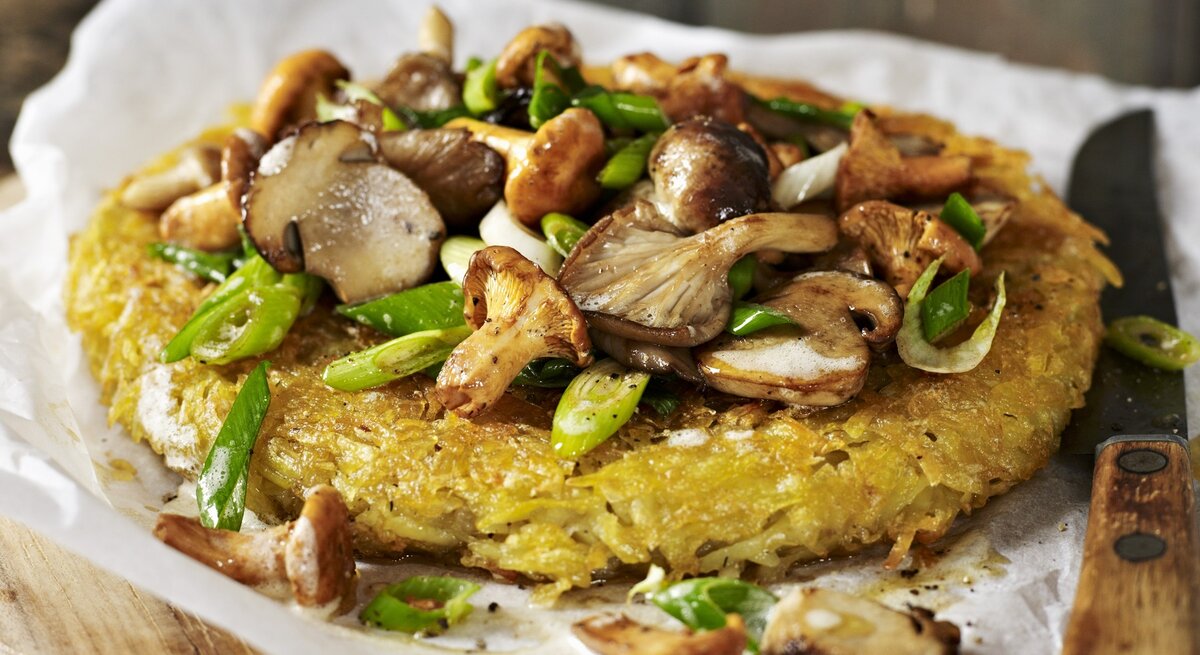 Ein Kartoffelrösti mit gemischten Pilzen auf Papier