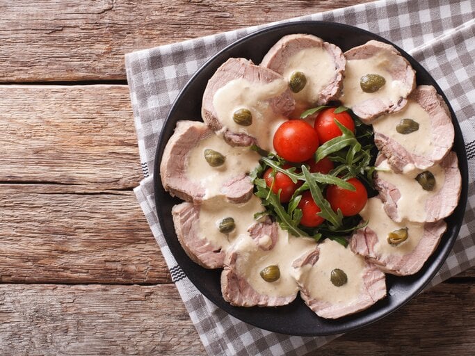 Draufsicht auf Vitello tonnato auf einem schwarzen Teller.  | © iStock/ ALLEKO