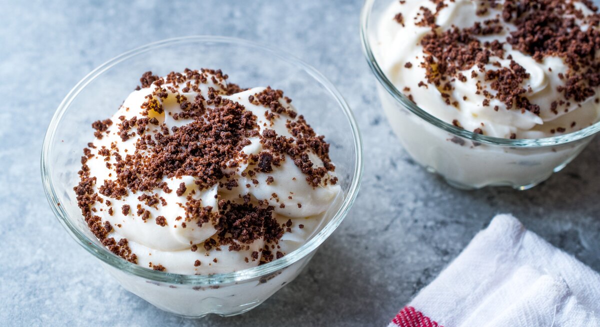 Weiße Quark-Bananen-Creme mit Kekskrümeön auf himmelblauer Oberfläche.