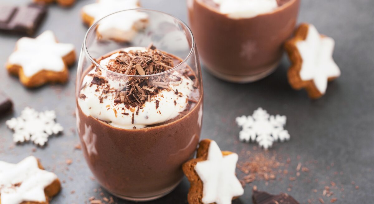 Weihnachtliche Schokoladen-Mousse im Glas, angerichtet mit Sahnecreme, Schokoraspel und Zimtsternen.