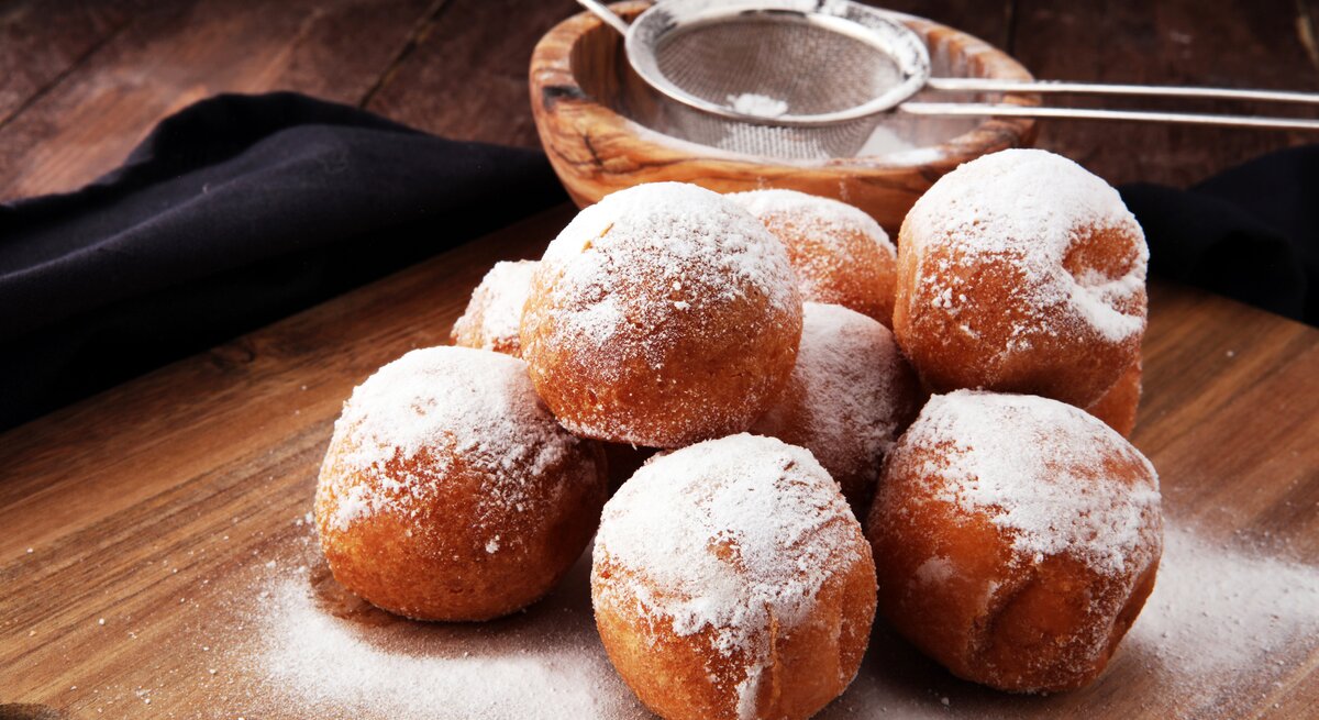 Mehrere mit Puderzucker bestäubte Quarkbällchen. 