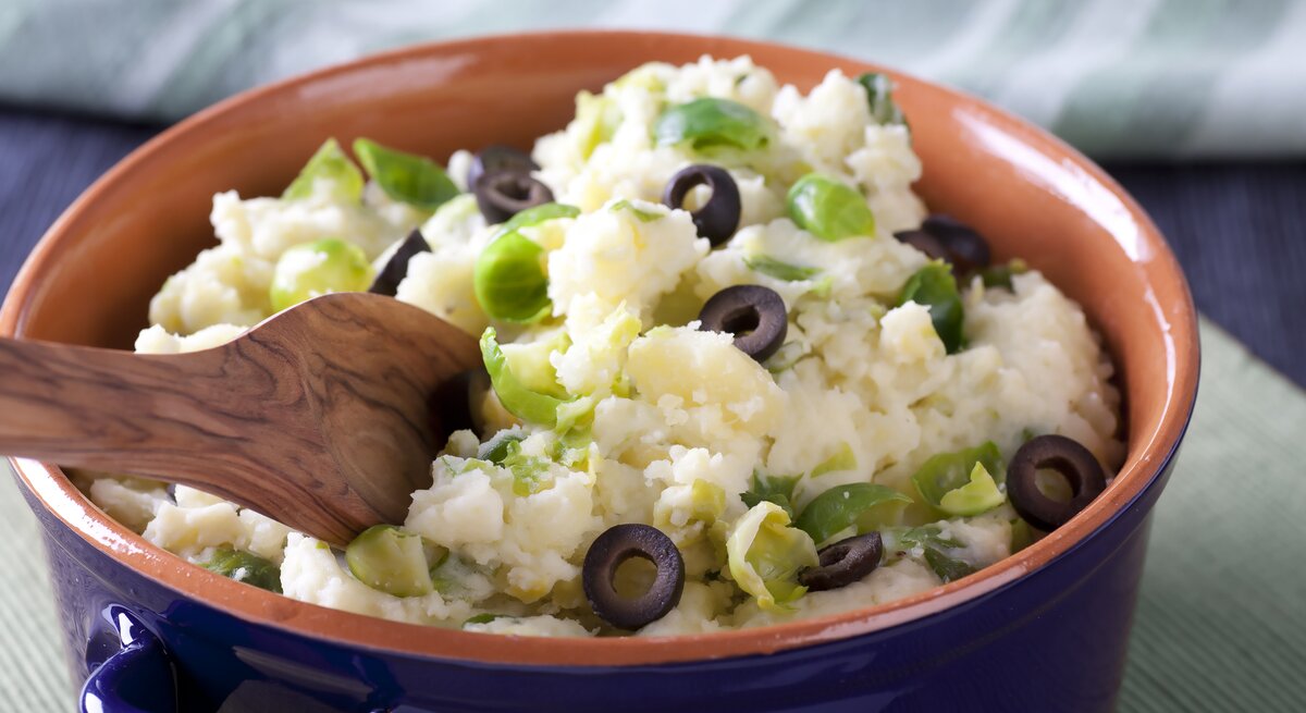 Tonschale gefüllt mit Kartoffelpüree mit Oliven und Rosenkohl.