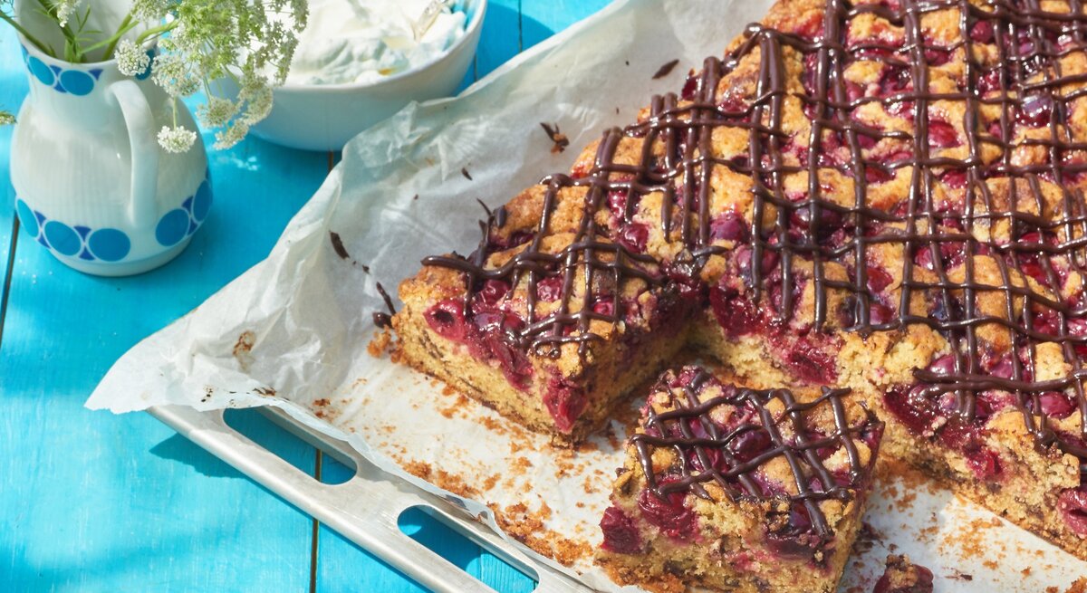 Kirschkuchen mit Schokochips vom Blech / Vase mit Blumen / Schale mit Sahne