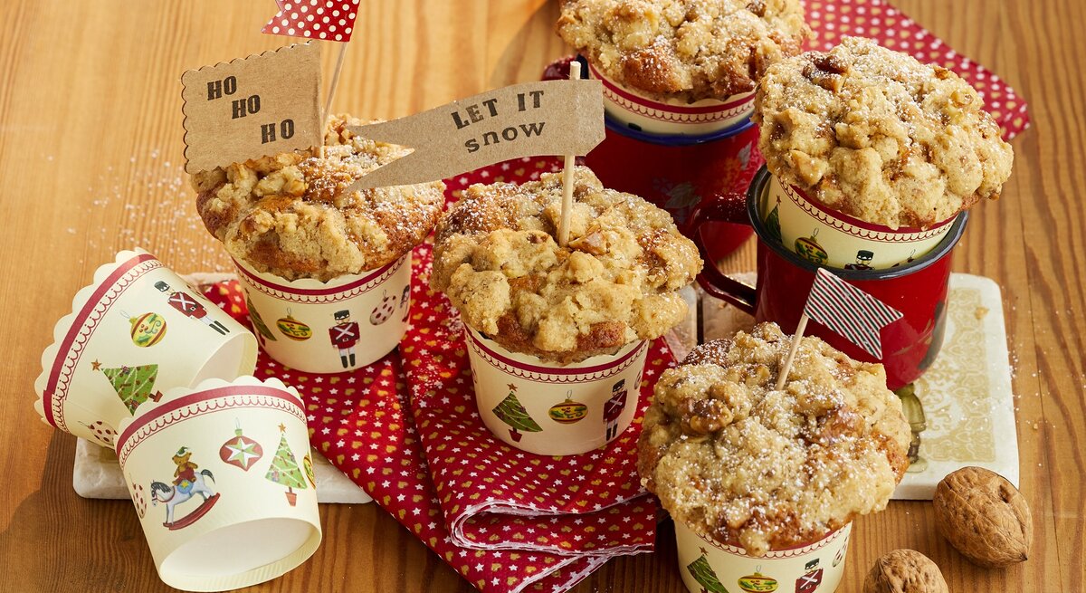 Bratapfel-Walnuss-Muffins auf einem hellen Holztisch mit roter Tischdecke. Alles von schräg oben fotografiert.