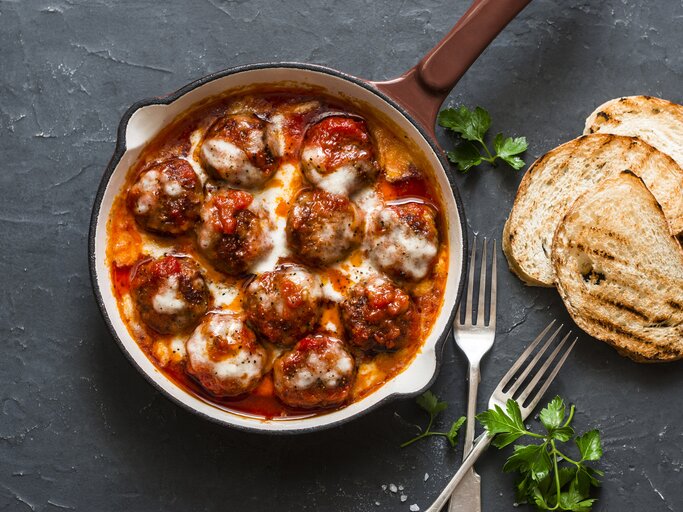 Hackbällchen Toskana überbacken mit Käse in Tomatensoße  in gusseiserner Form.  | © iStock/ OksanaKiian