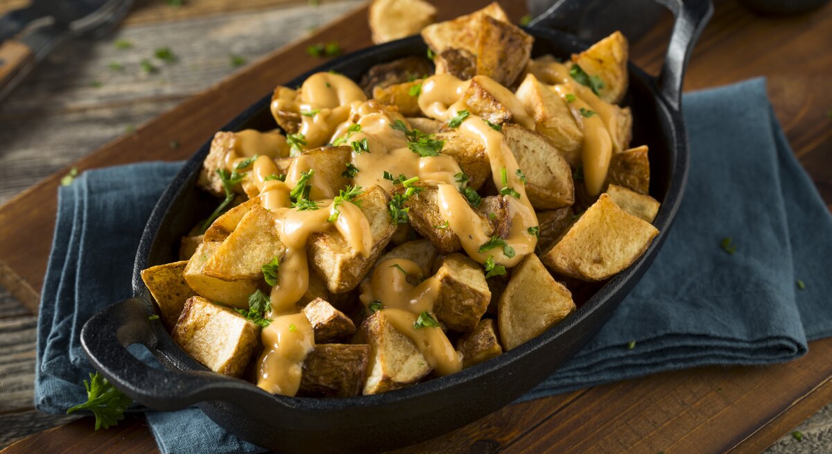 Patatas bravas mit Soße in schwarzer Schale.
