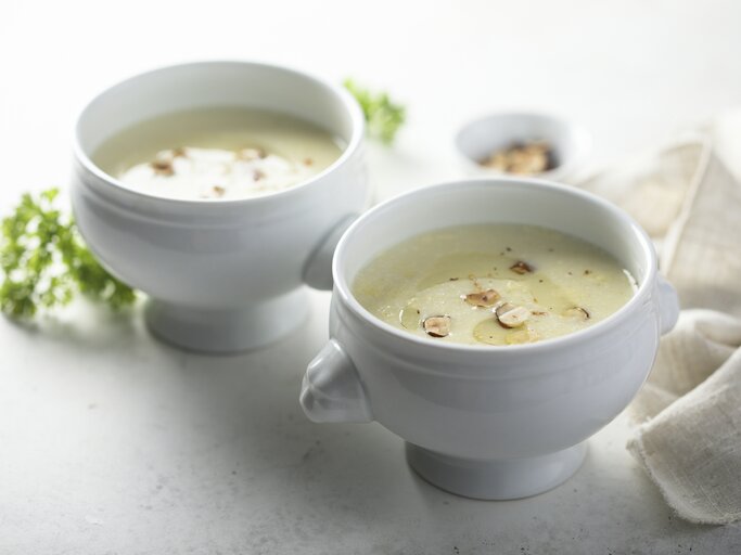 Weiße Suppenschalen gefüllt mit Kohlrabicremesuppe, garniert mit Haselnuss.  | © iStock.com/Mariha-kitchen