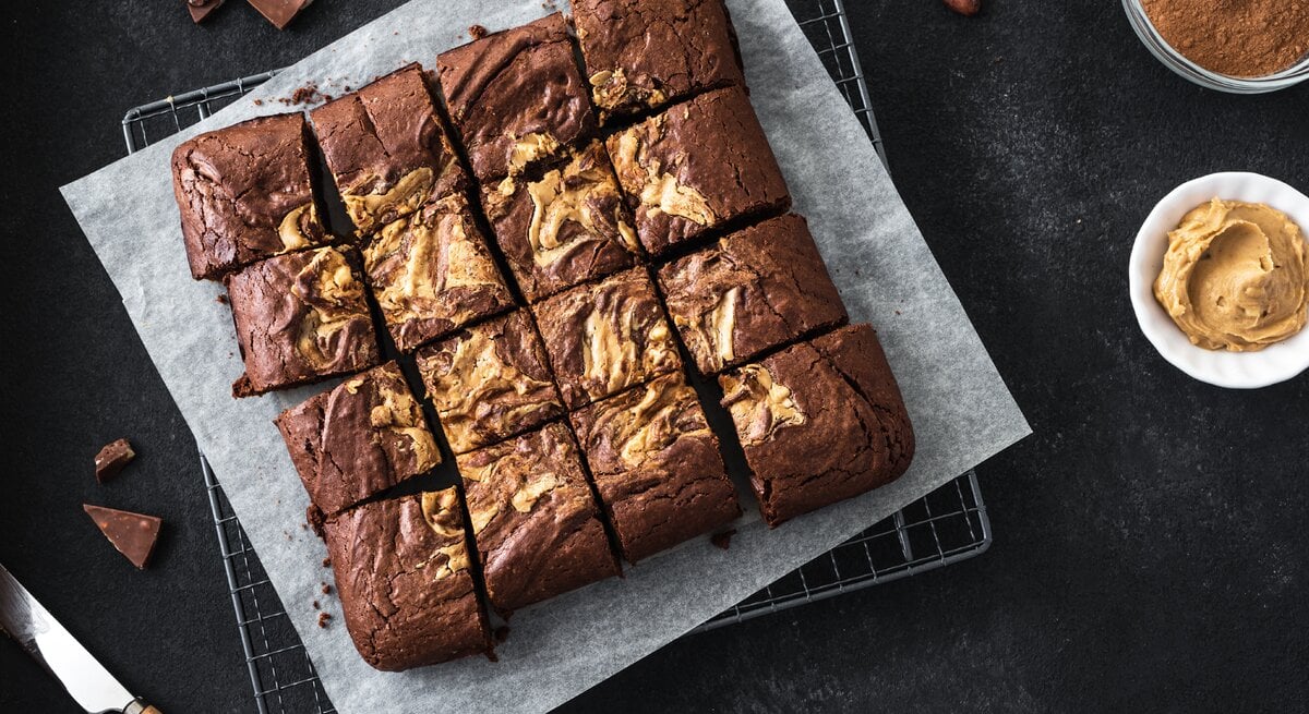 Draufsicht auf Erdnussbutter-Schokobutter-Brownies auf dunklem Tisch. 