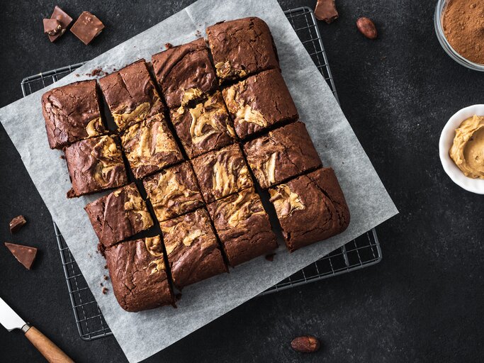 Draufsicht auf Erdnussbutter-Schokobutter-Brownies auf dunklem Tisch.  | © GettyImages/Oksana Bratanova