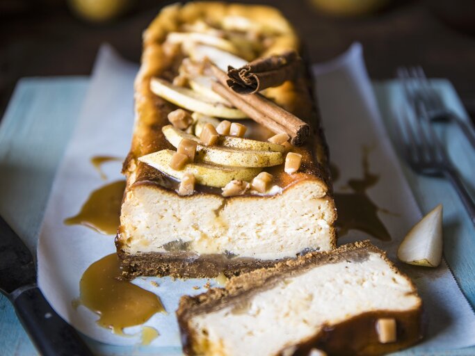 Der Toffee-Birnen-Käsekuchen angeschnitten auf einer bläulichen Serviette von vorne fotografiert. | © StockFood / Hendey, Magdalena