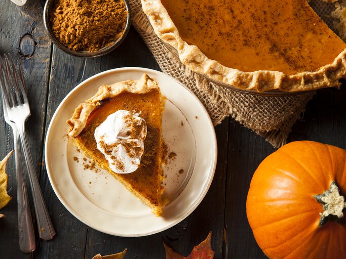 Angeschnittenes Stück amerikanischer Kürbiskuchen mit einem Klecks Sahne. | © iStock/ bhofack2