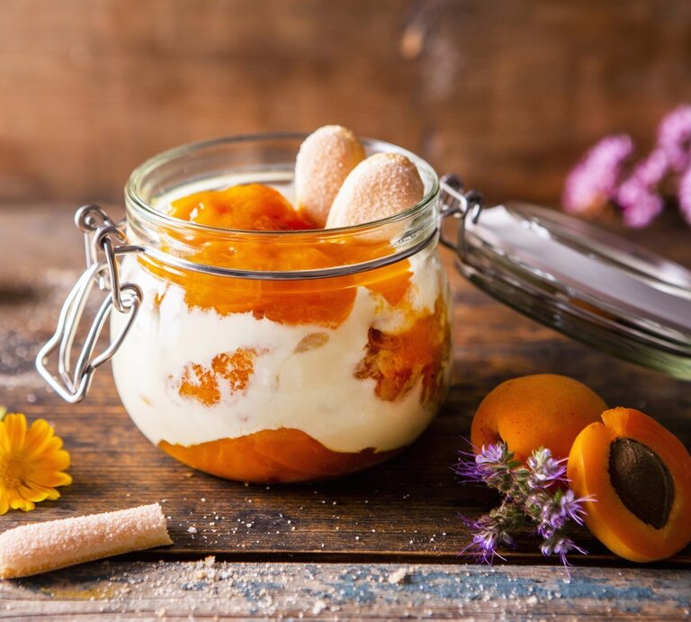 Aprikosen-Tiramisu in einem Einmachglas. Daneben verschiedene Zutaten und Blumen. | © StockFood / Krimshandl-Tauscher, Sandra