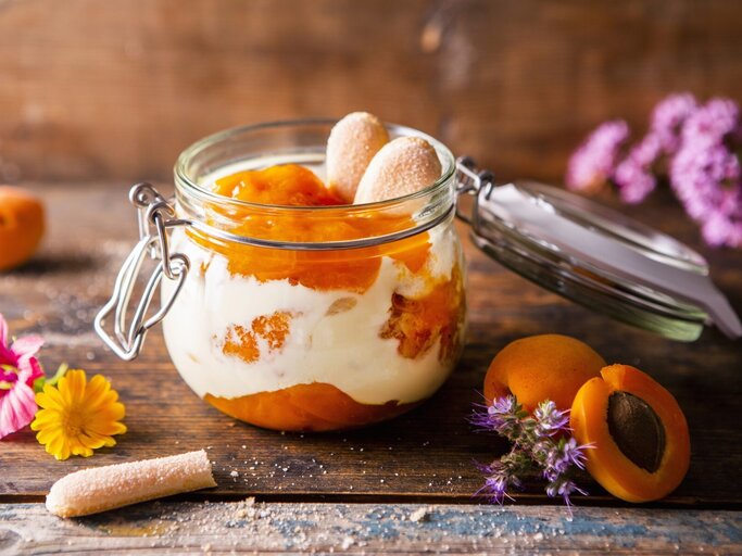 Aprikosen-Tiramisu in einem Einmachglas. Daneben verschiedene Zutaten und Blumen. | © StockFood / Krimshandl-Tauscher, Sandra
