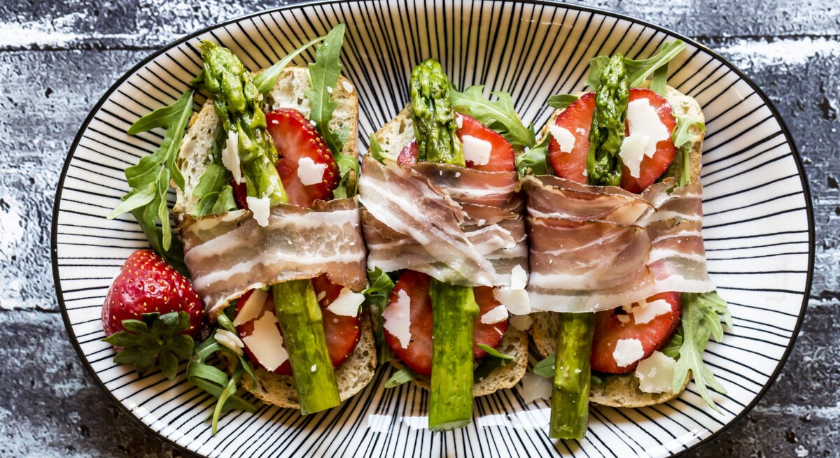 Bruschetta belegt mit Spargel, Erdbeeren, Rucola, Parmaschinken und Parmesan.