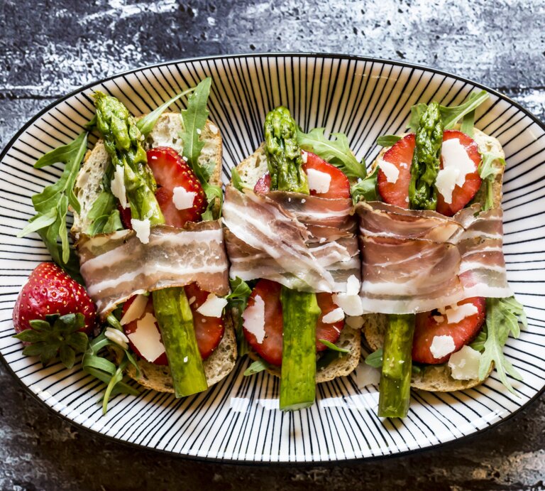 Bruschetta belegt mit Spargel, Erdbeeren, Rucola, Parmaschinken und Parmesan. | © Getty Images/ Westend61