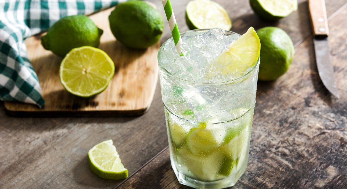Ein Glas gefüllt mit selbst gemachtem Caipirinha - daneben die passenden Zutaten.